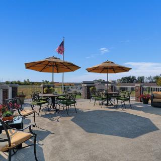 An inviting outdoor patio area with tables, chairs, and umbrellas under a clear blue sky.