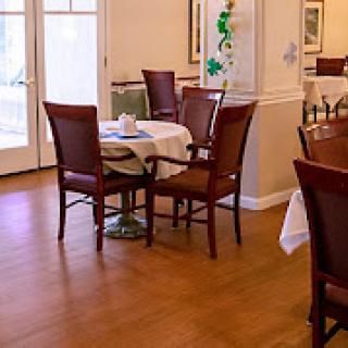 A cozy dining room setting with neatly arranged tables and chairs, featuring a wooden floor.