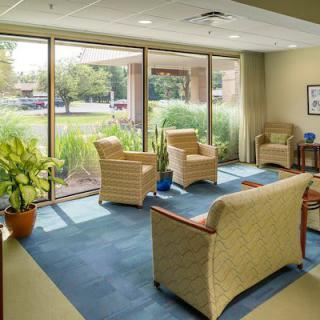 A well-lit waiting room with comfortable seating, large windows, and indoor plants.