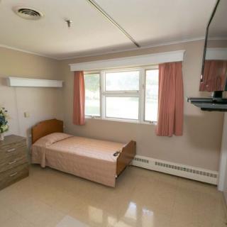 A simple hospital room with a single bed and a window with curtains.