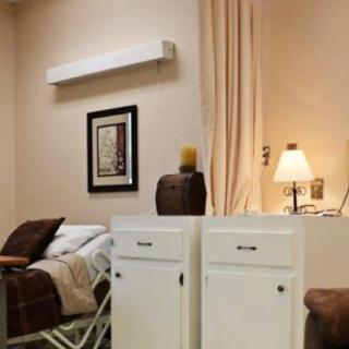 A cozy hospital room with a bed, lamp, and decorative elements.