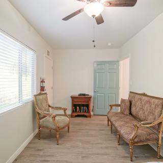 A cozy living room with comfortable seating, a ceiling fan, and natural light from a large window.
