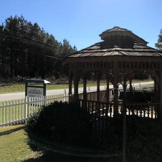 A picturesque gazebo set in a sunny outdoor environment, surrounded by trees.