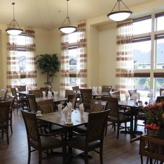 A well-lit dining area with neatly arranged tables and chairs, featuring decorative elements and large windows.