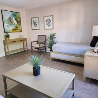 A modern and minimalist living room with a daybed, artwork, and decorative plants.