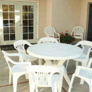 A patio area with a white round plastic table surrounded by matching chairs.