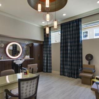 A modern salon interior featuring a stylish mirror, comfortable chairs, and elegant lighting.
