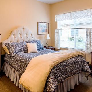 A cozy bedroom with a bed, natural lighting, and decorative elements.