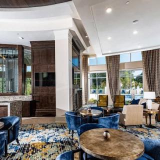 A stylish lounge area featuring modern decor with ample seating and large windows.