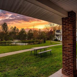 A picturesque sunset over a serene park with a bench and pathway.