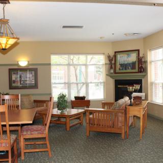 A cozy living room area with wooden furniture, a fireplace, and large windows.
