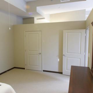 A minimalist bedroom with two doors and a ceiling fan.