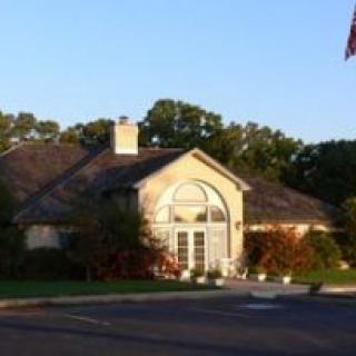 A suburban house with a driveway, surrounded by trees on a sunny day.