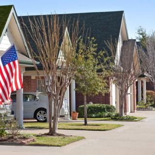 A suburban neighborhood with neatly lined houses and an American flag displayed.