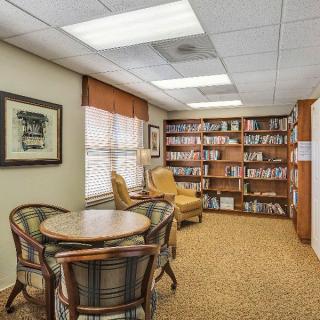 A cozy library reading area with bookshelves, a table, and chairs.