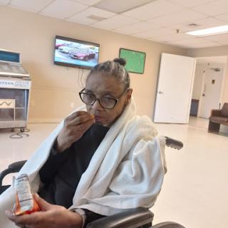 A person in a wheelchair enjoying a snack in a healthcare facility.