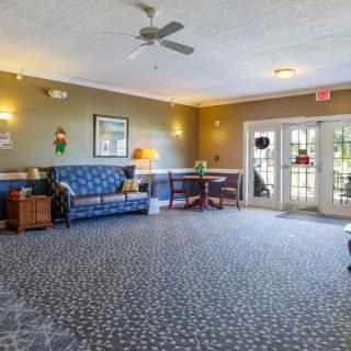 A cozy lobby area with a sofa, carpeted floor, and ceiling fan.