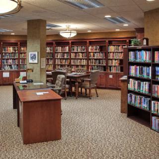 A cozy library with wooden shelves filled with books and a dedicated reading area.