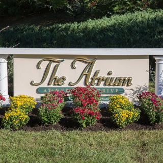 A decorative sign reading 'The Atrium' surrounded by colorful flowers and greenery.