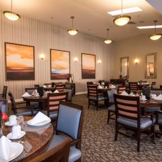 An elegant dining room setup with neatly arranged tables and chairs, decorated with framed artwork on the walls.