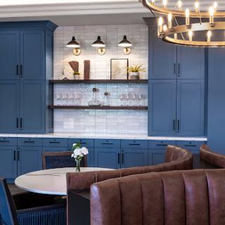 A stylish and modern kitchen featuring blue cabinetry, elegant lighting, and a cozy dining area.
