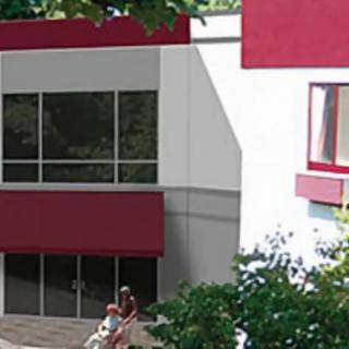 A modern building exterior with large windows and a person nearby.