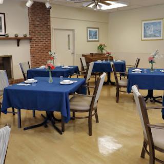 A cozy dining area featuring blue tablecloths and comfortable chairs, set for a meal.