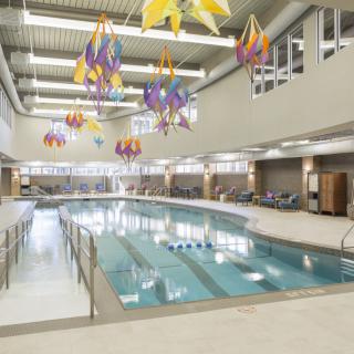 An indoor swimming pool with colorful ceiling decorations and seating area.