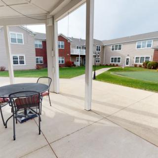 A patio area with seating overlooking a courtyard in an apartment complex.