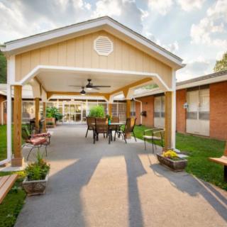 A cozy outdoor patio area with a gazebo, surrounded by a garden and buildings.