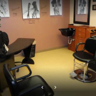 A cozy salon interior with styling chairs, a sink, and wall art.