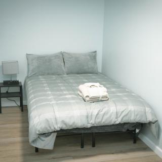 A minimalist bedroom with a neatly made bed and a small nightstand with a lamp.