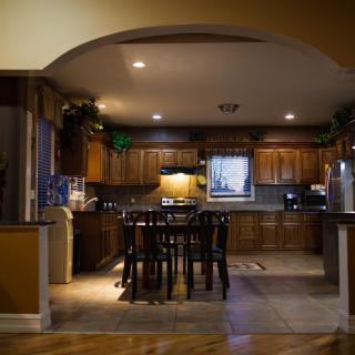 A cozy kitchen with wooden cabinets and a dining area under warm lighting.