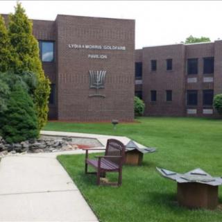 A brick office building with a landscaped lawn and benches.