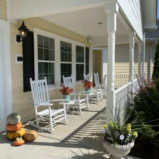 A charming front porch with rocking chairs, decorated for autumn with pumpkins and flowers.