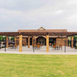 A charming outdoor restaurant with a spacious patio and a well-maintained grassy area.