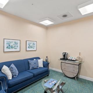 A cozy waiting room with a blue sofa and a coffee station.
