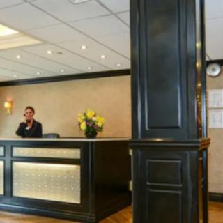 A hotel reception area with a receptionist sitting at the front desk.