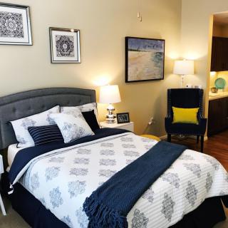 A cozy bedroom with stylish decor, featuring a neatly made bed, decorative pillows, and complementary artwork on the walls.
