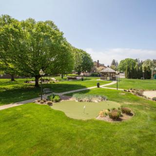 A beautifully landscaped park with lush green lawns and trees under a sunny sky.
