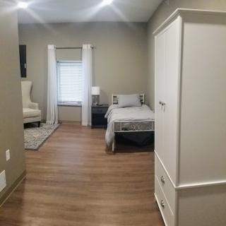 A minimalist bedroom with wood flooring and neutral color scheme.