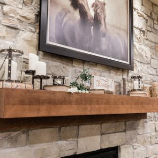 A beautifully styled fireplace mantel featuring a stone wall, decorative candles, and an elegant horse painting.