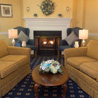 A cozy living room with a fireplace, two sofas, armchairs, and a decorated coffee table.