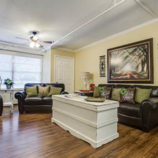 A cozy living room with leather sofas, a white coffee table, and framed artwork on the wall.