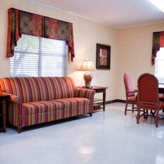 A cozy living space featuring a striped sofa, a dining area with wooden chairs, and soft lighting.