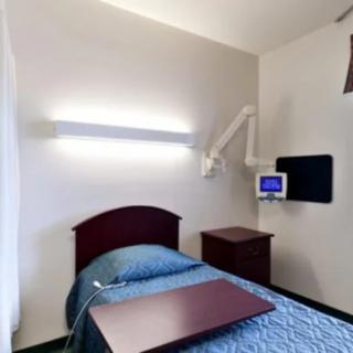 A hospital room with a single bed and medical equipment.