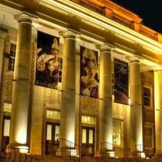 A grand building illuminated at night featuring large columns and elegant lighting.