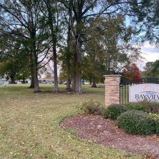 Entrance to a well-maintained park with lush greenery and tall trees.