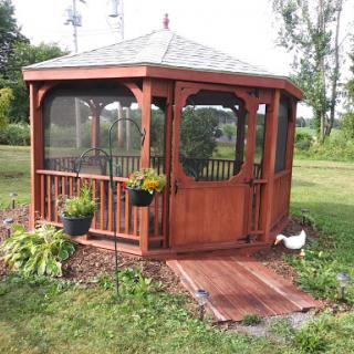 A charming wooden gazebo surrounded by lush greenery and decorative plants, creating a serene outdoor space.