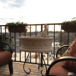 A cozy balcony setting with comfortable seating, planters, and a beautiful city view during sunset.